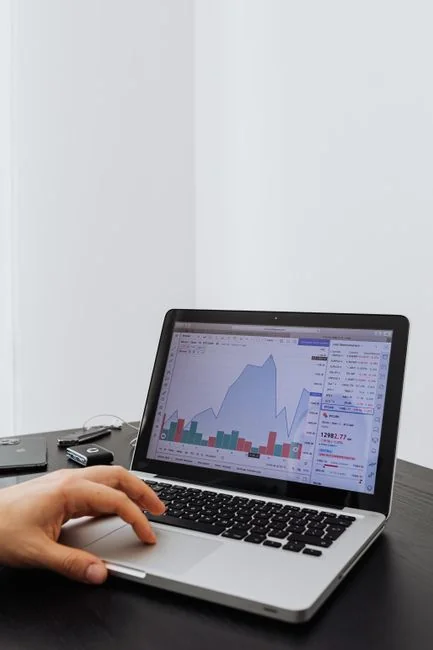 Insightful business analytics with graphs on monitor, papers, and phone calculator.
